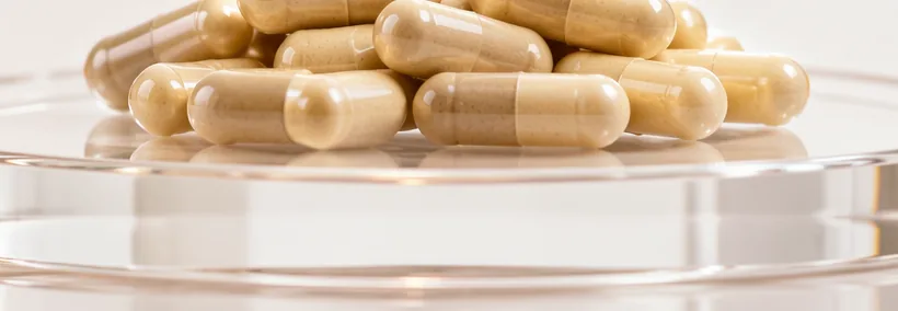 Filled enzyme-blend capsules on a clear glass dish